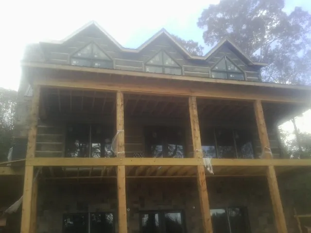 Dormers and porch framing on a large log home under construction — Roof Coating work by our crew in Guilford