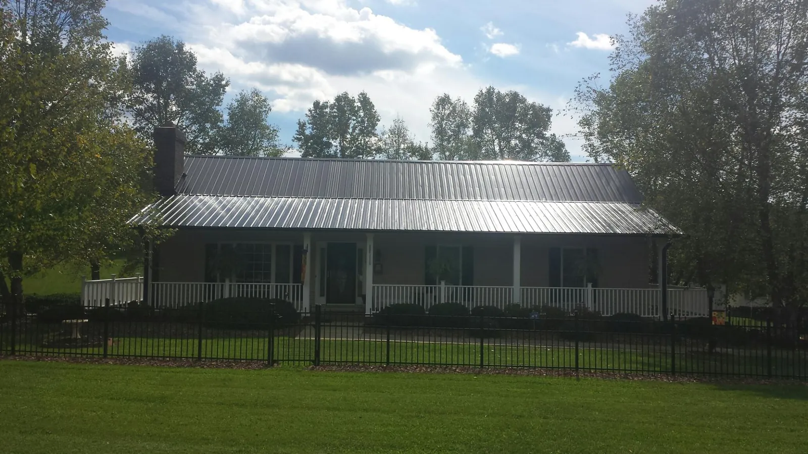 Gray metal roof on a brick ranch with a full width front porch — Gutter Guard Installation work by our crew in Guilford